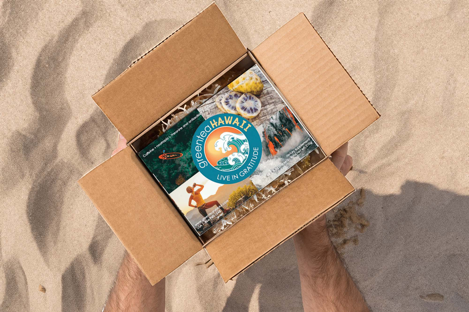 Image of a greenteaHAWAII subscription box being opened with a sandy background